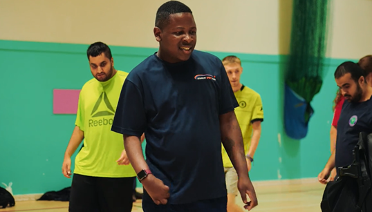 A coach and his group are taking part in basketball in a sports hall.