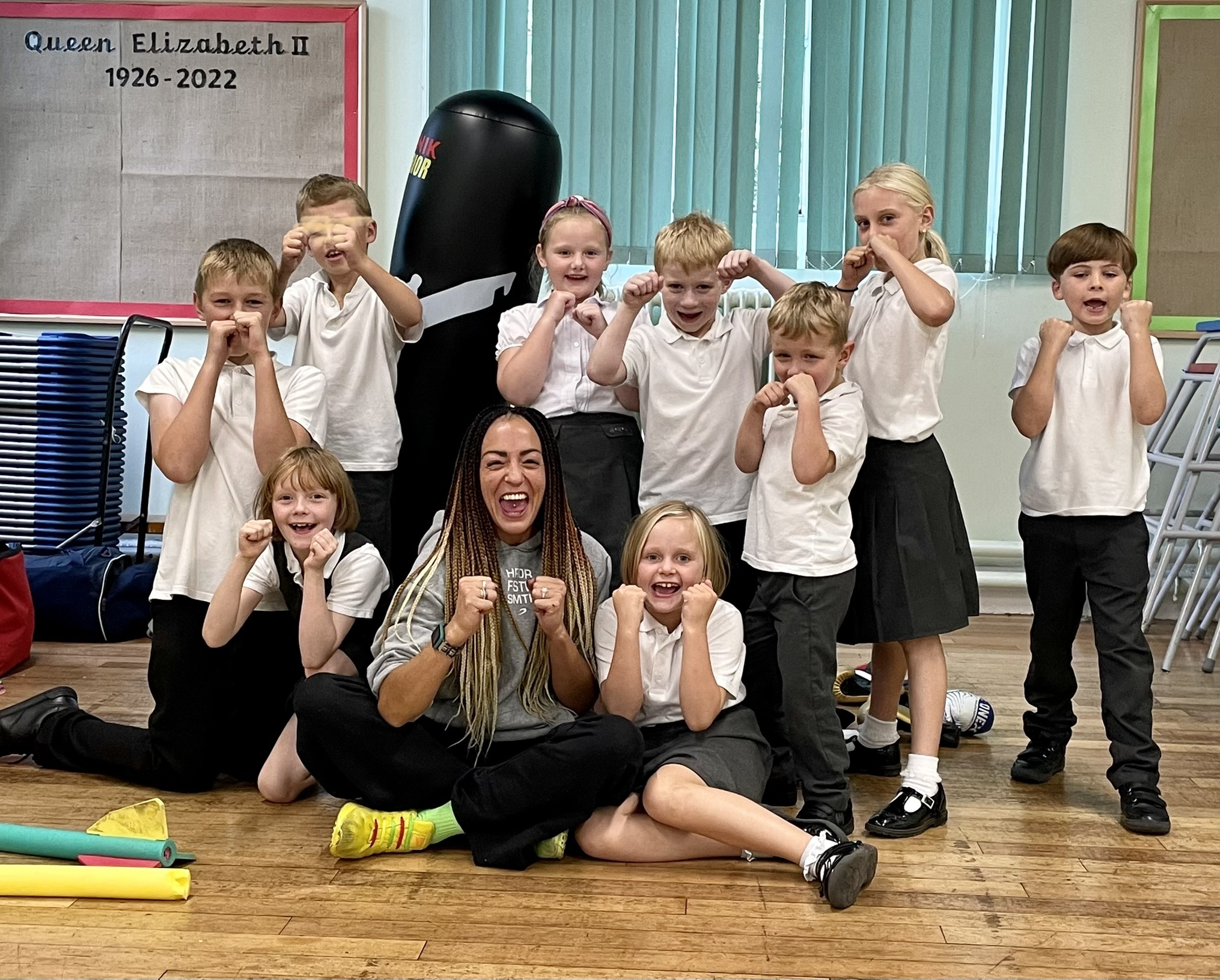 Luiz Faye in a boxing pose with nine schoolchildren