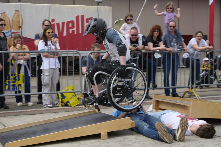 Tomas Woods propels his wheelchair off a ramp, over two people lying on the floor and onto another ramp in a daring trick