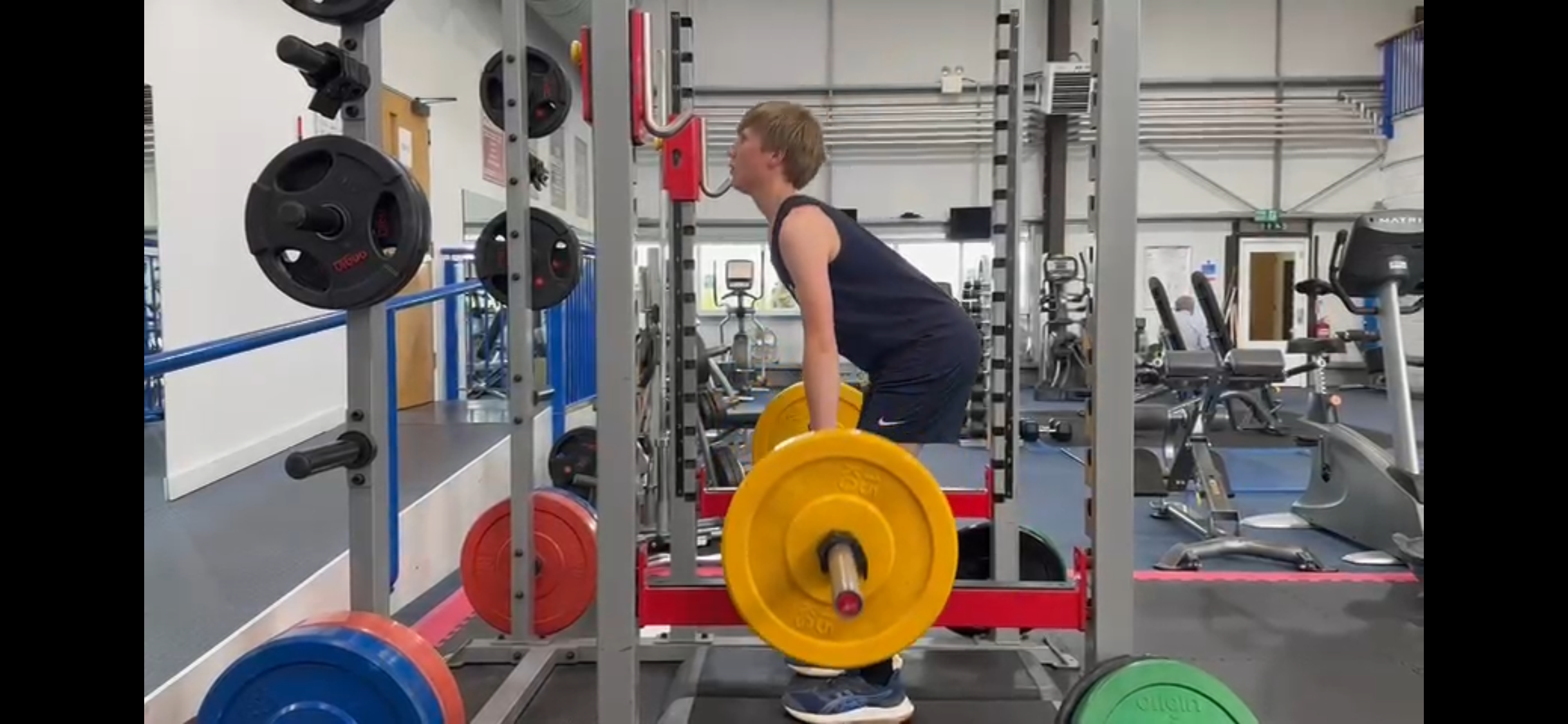 A side-on view of Isaac lifting weights during a gym session