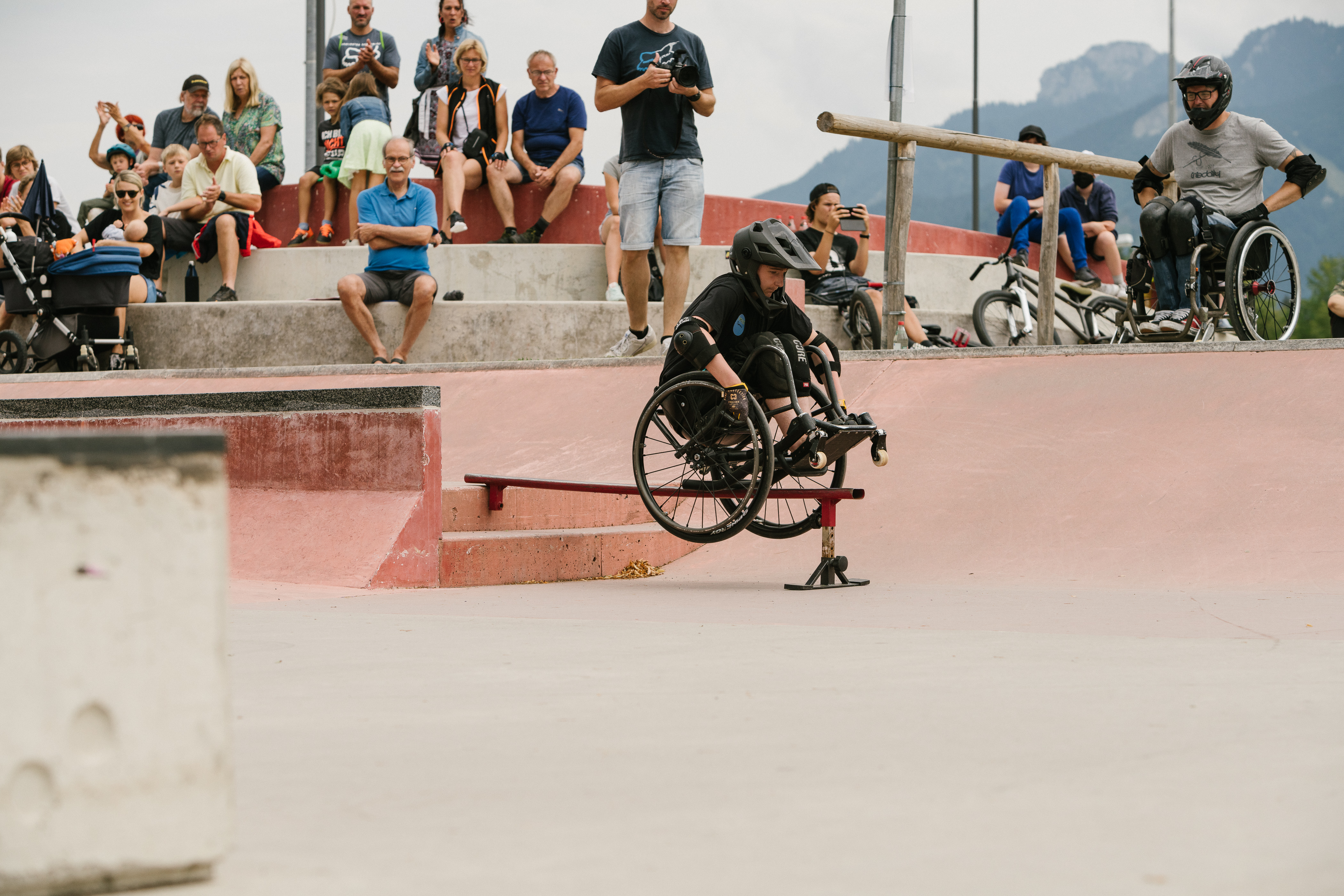 Tomas Woods performs an airborne trick with crowds watching in the background at a competition