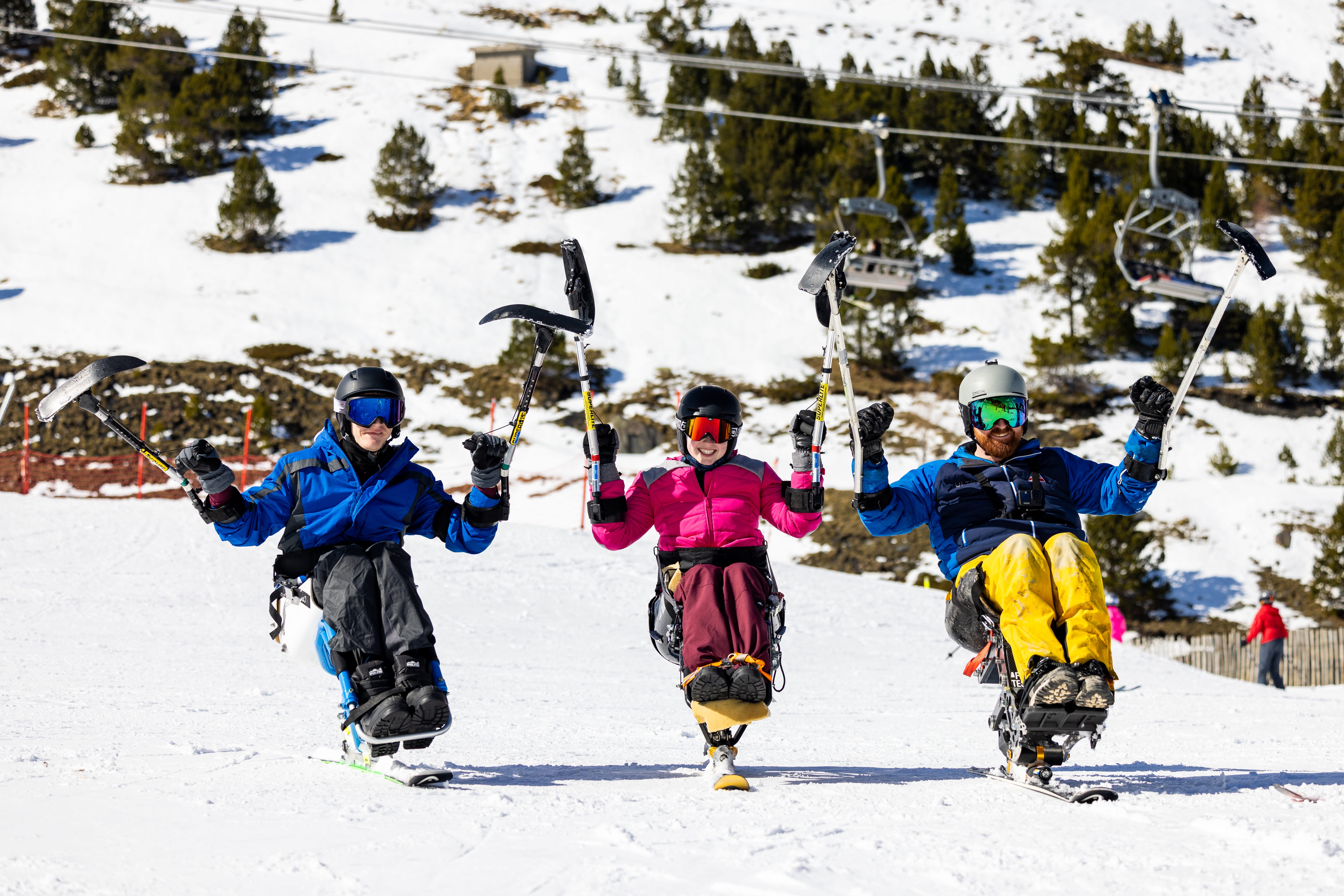 3 sit skiers positioned side by side on a flat slope in the mountains