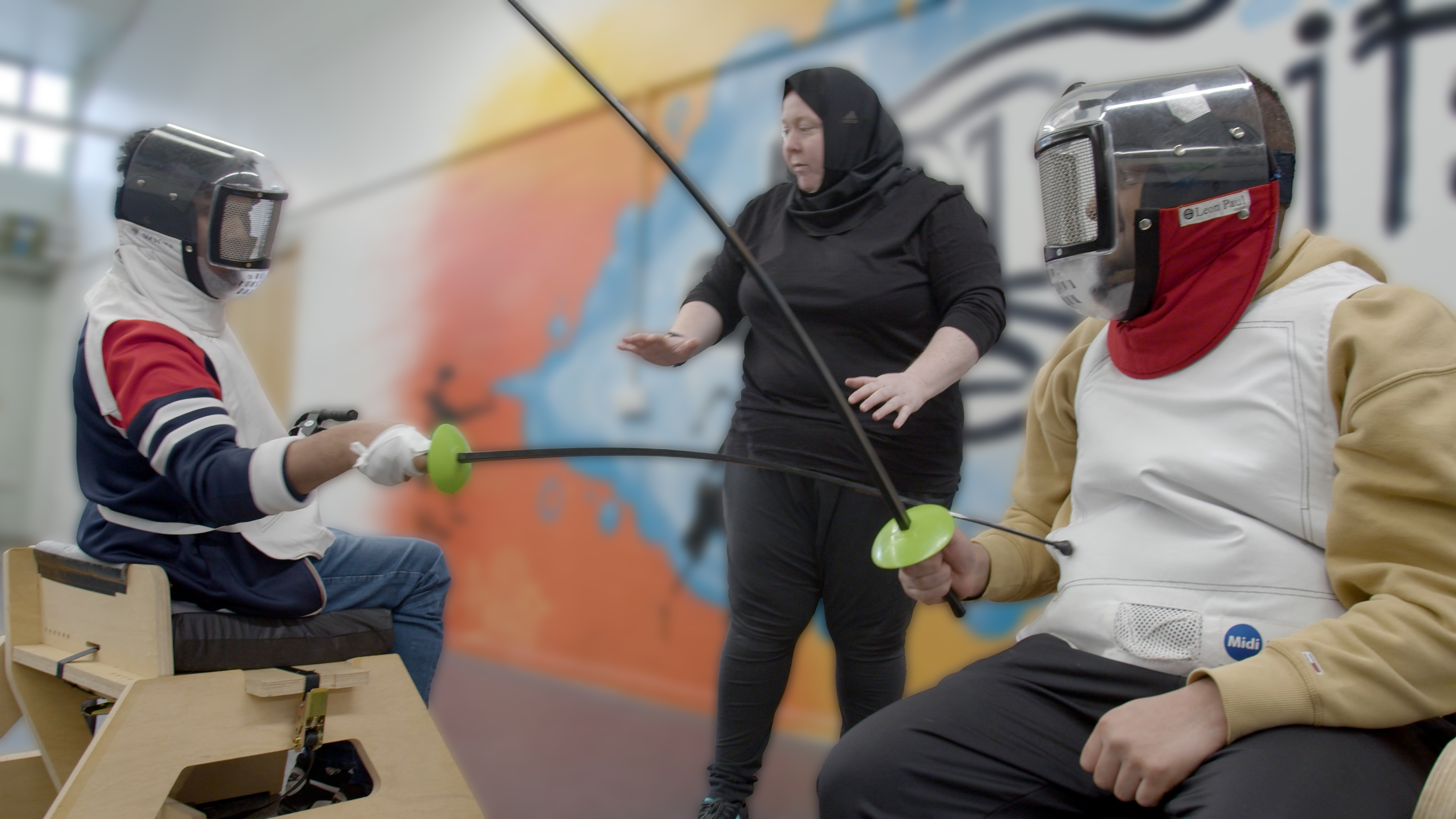 2 seated fencers mid bout, with swords touching and dressed in full protective gear.