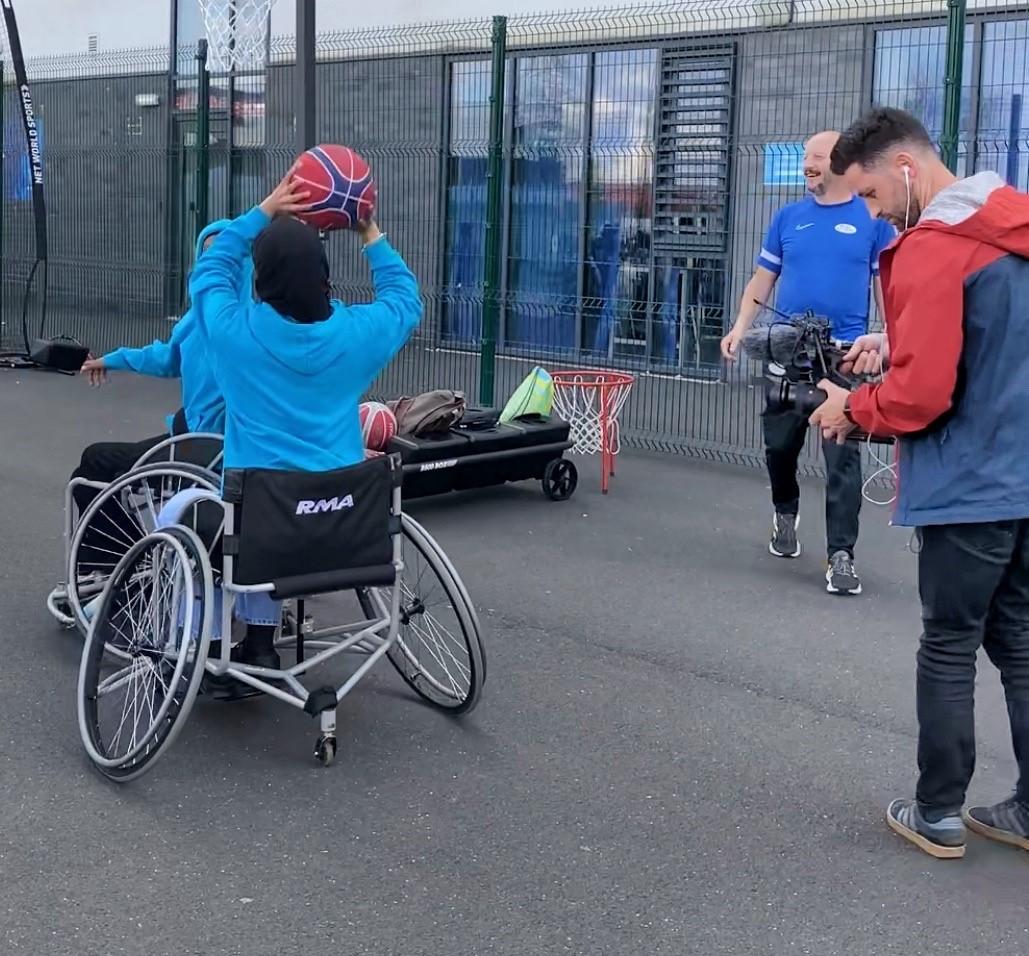 Videographer filming a wheelchair basketball game