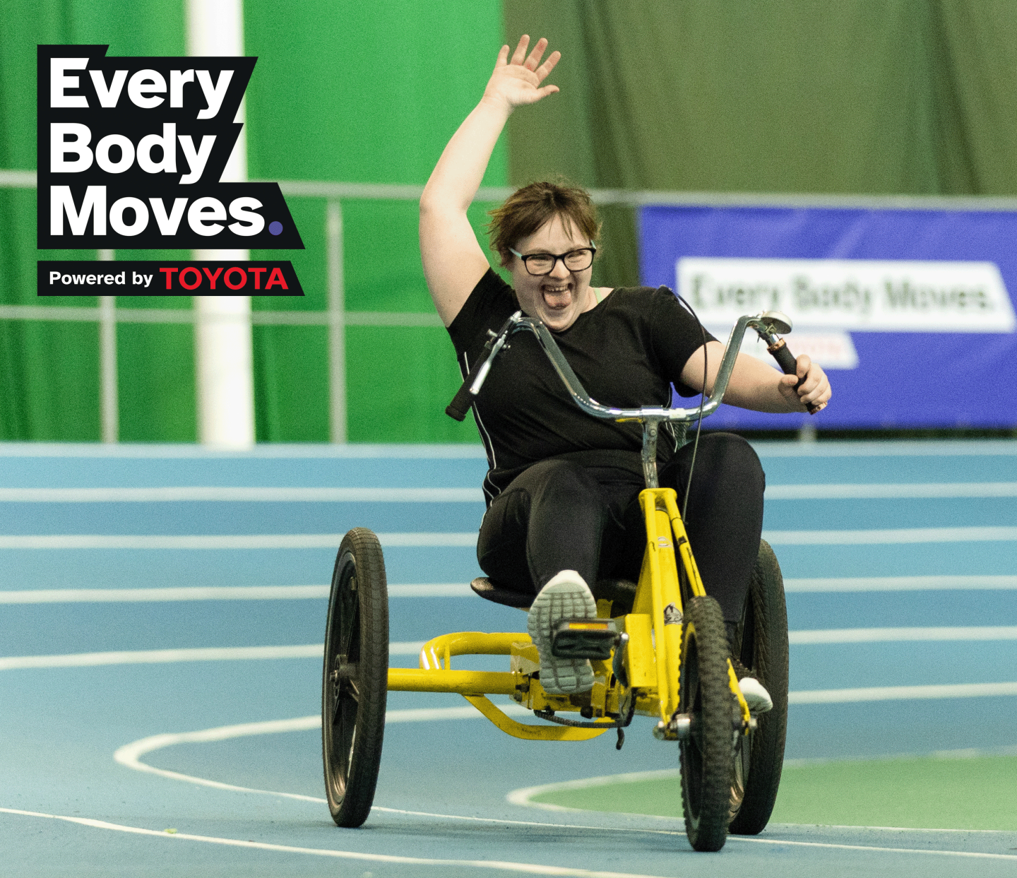 Woman on a tricycle having a great time going around an athletics track