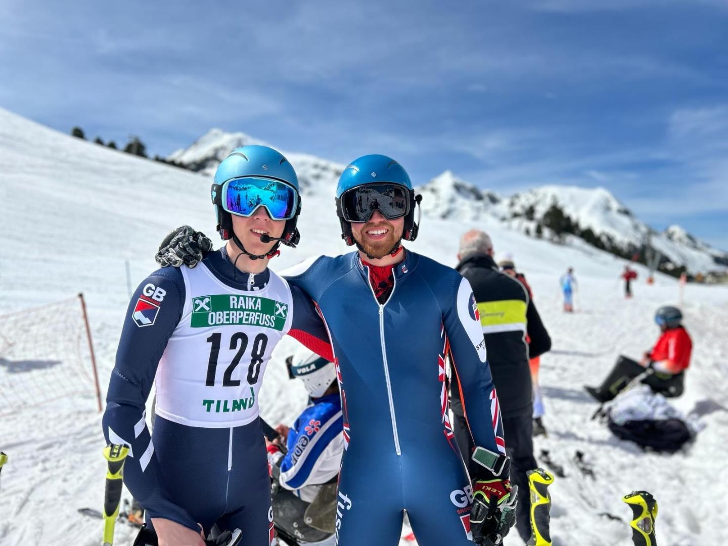 Sam Cozens and guide Adam Hall on a snow-covered mountain slope. Adam has his arm around Sam and they are both looking at the camera.