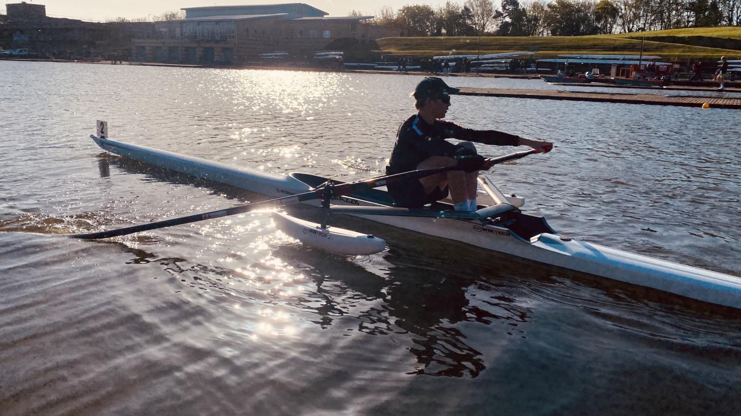 Isaac Clarkson during a rowing training session with the sunlight shimmering on the water