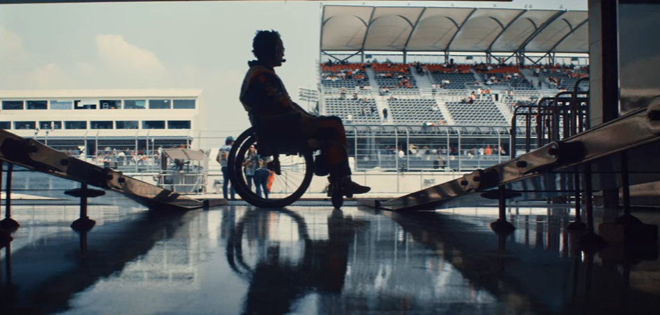 Silhouetted wheelchair user, framed side on, in the garage entry of a pit lane at a race track