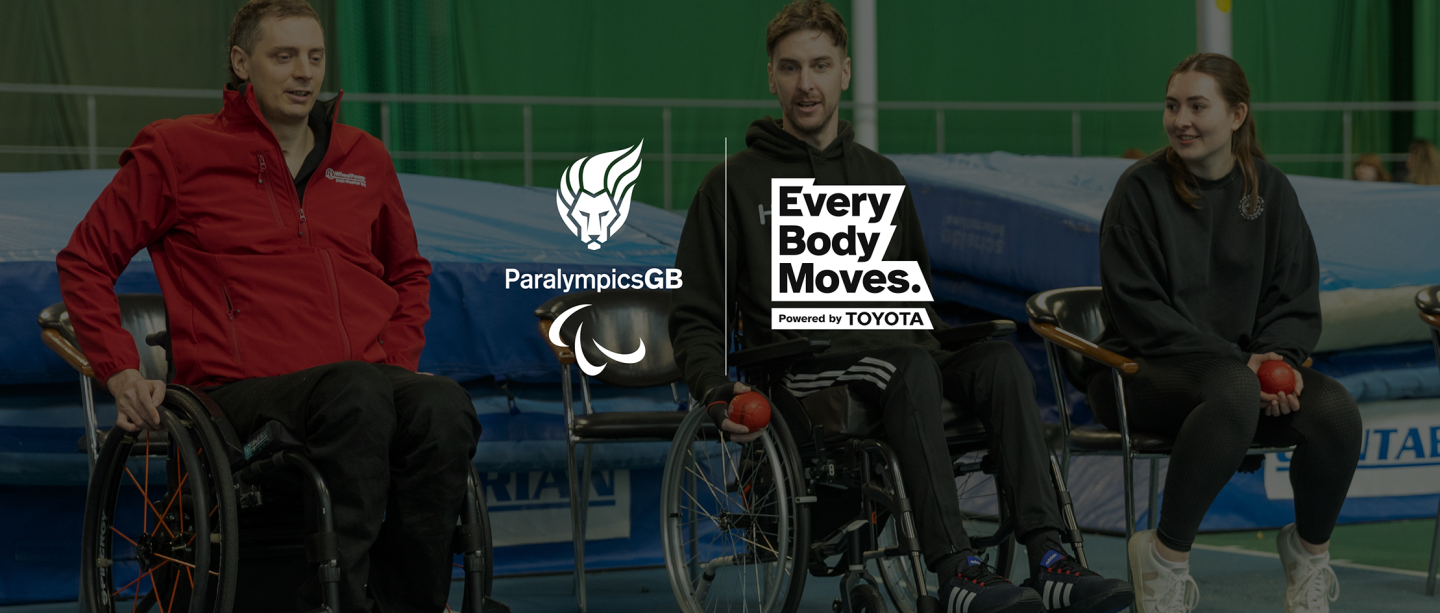 A white ParalympicsGB Lion logo with Agitos adjacent to a white Every Body Moves powered by Toyota logo. This logo lock up is embossed over a game of Boccia in a large sports hall with three seated players looking on.