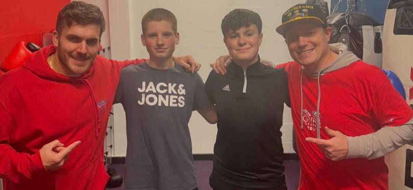 Dan Powell with three young boxers, all looking at the camera with their arms around each other