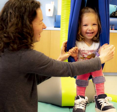 Child in a swing with her mother