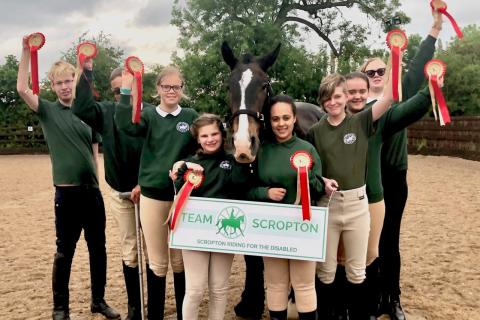 Group of riders with rosettes clustered around a horse