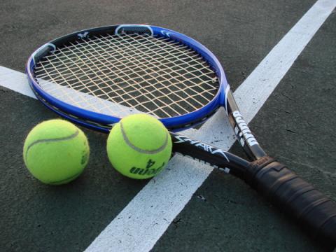 tennis racket and 2 tennis balls lying on a tennis court