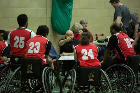 A frenford coach instructing his players during a wheelchair basketball match. 