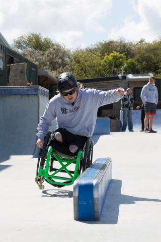 WCMX rider grinds rail with wheel in outdoor skatepark