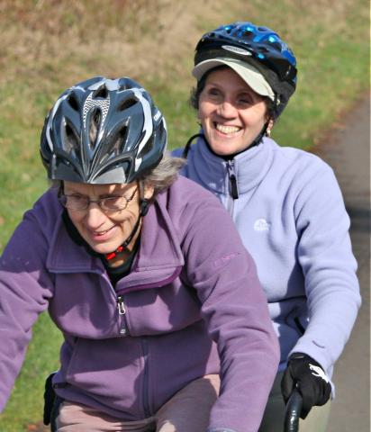 Two women riding a tandem in countryside