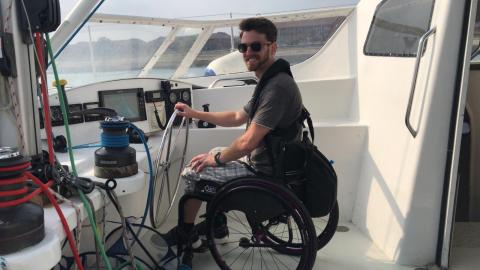 Young wheelchair using at the helm of a sailing boat 