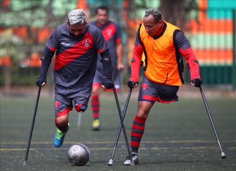 2 lower limb amputee footballers both using crutches, fight for the ball during a training session