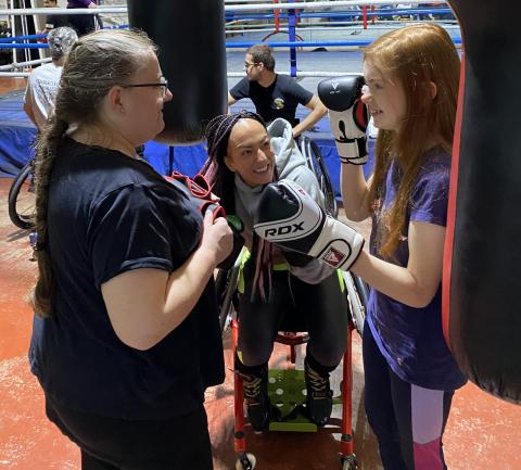 Two female adaptive boxers being coached ring side
