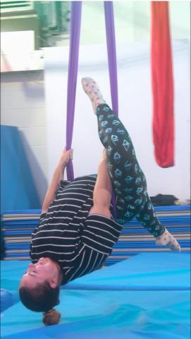 inclusive aerial silks participant, inverted and suspended over a mat