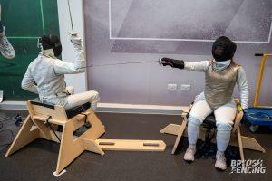 Seated fencers mid bout in an infoor setting, using the new SwordSeat