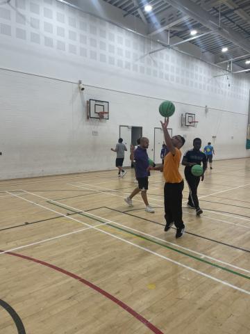 adaptive basketball player mid shot on an indoor court