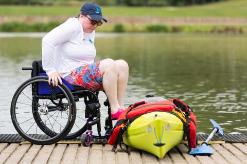 Adaptive kayak session, wheelchair user transferring to the kayak on a lakeside
