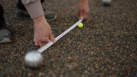 petanque scoring - a tape measure being used to record the distance between the jack target ball and the player's ball