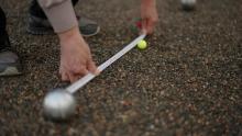 petanque scoring - a tape measure being used to record the distance between the jack target ball and the player's ball