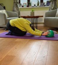 Adaptive pilates participant kneeling on the floor holding a ball
