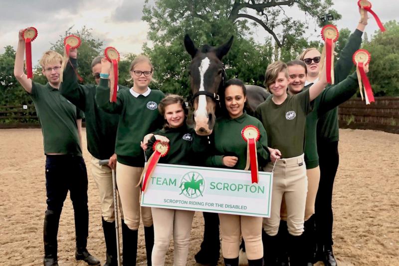 Group of riders with rosettes clustered around a horse