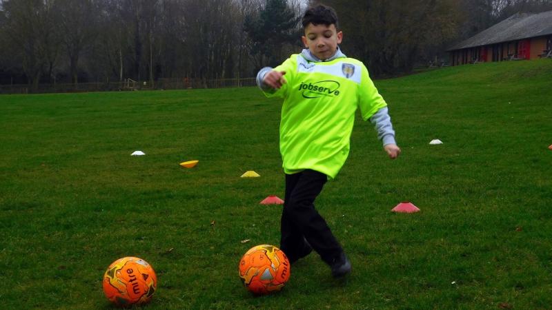 young boy kicking a football