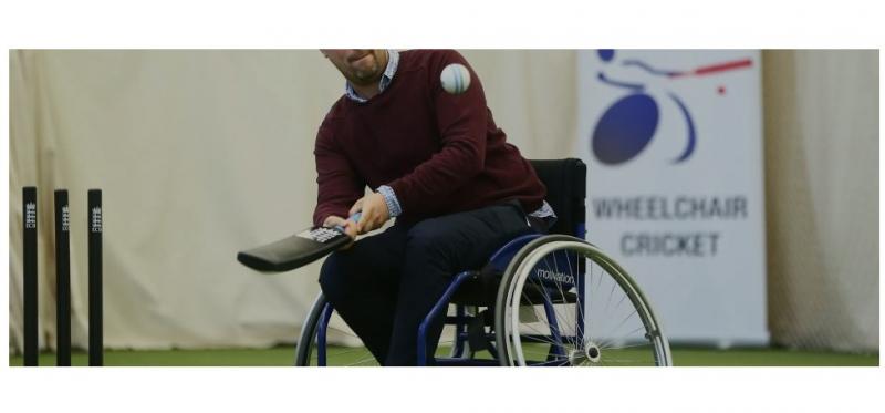 male wheelchair user hitting cricket ball with cricket bat