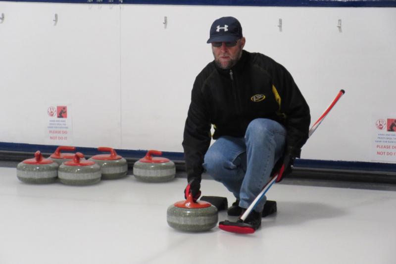 Founder and blind member of SDGC kneeling on the ice about to push forward his curling stone.