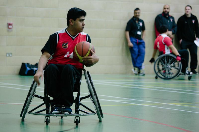 a Wheelchair basketball player in possession of the basketball searching for options