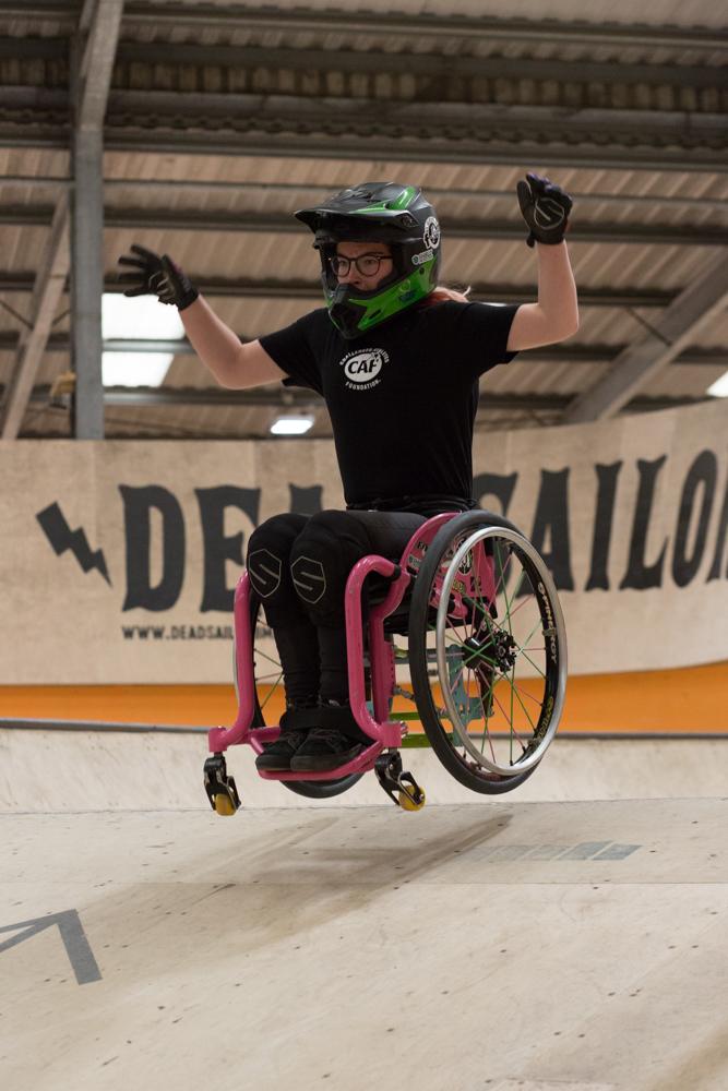 WCMX rider with arms up doing a jump over a ramp in the indoor skatepark 