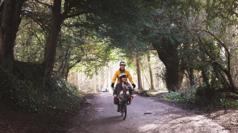 Rider and client cycling through sunny Leigh Woods, Bristol