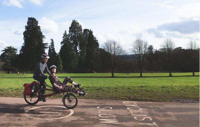 Rider and client cycling along cycle path in Ashton Court, Bristol