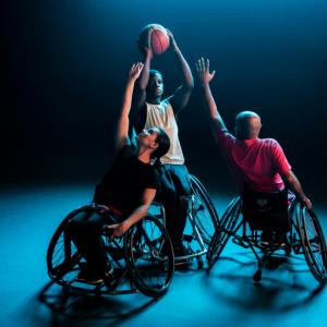 A wheelchair basketball player takes a shot while two others try to block him
