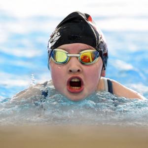 female swimmer with goggles and a hat takes a breath