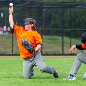 Two blind baseball players blindfolded, one catching the ball