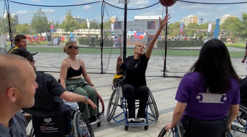 The Club of the Month winners trying out wheelchair basketball. One of them reaching to catch the ball.