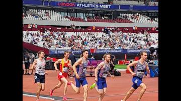 Kieran O'Hara running at the London Stadium on a red track wearing a white singlet and blue shorts