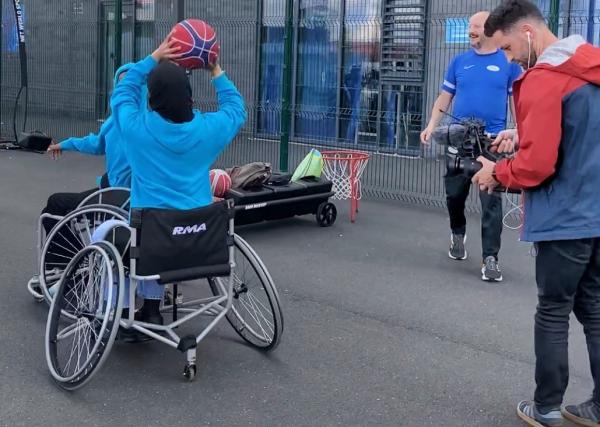 Videographer filming a wheelchair basketball game