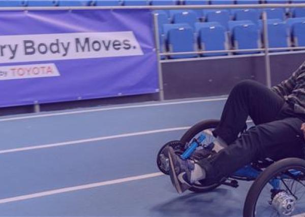 Image of a male participant on a recumbent trike, on an indoor track.