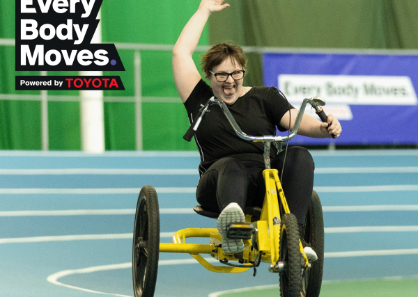 Woman on a tricycle having a great time going around an athletics track