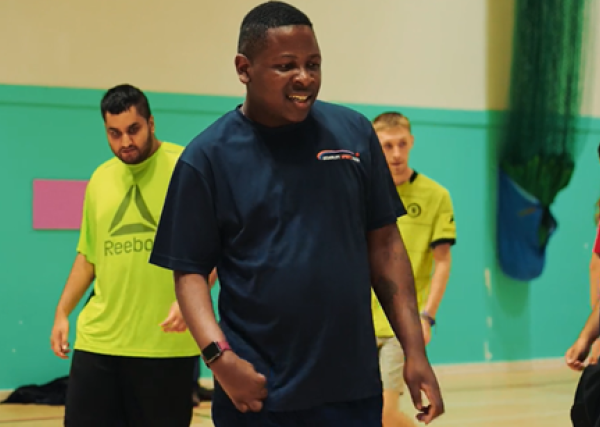 A coach and his group are taking part in basketball in a sports hall.