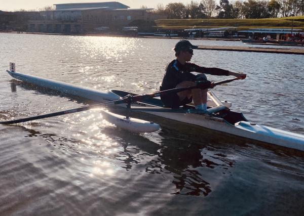 Isaac Clarkson during a rowing training session with the sunlight shimmering on the water