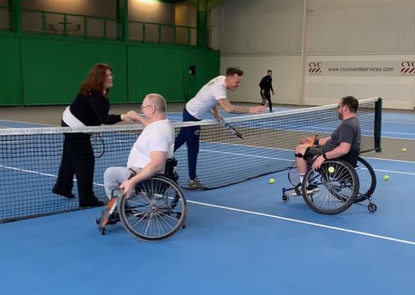 4 adaptive tennis players shaking hands at the net post game