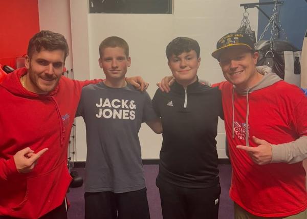 Dan Powell with three young boxers, all looking at the camera with their arms around each other